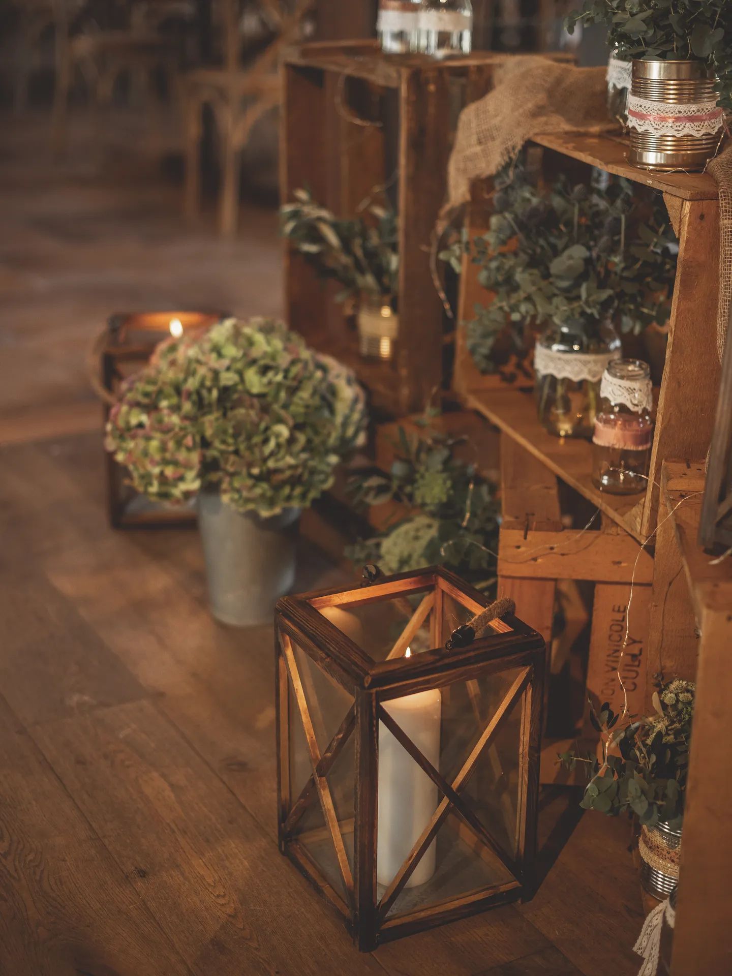 Lanterne en bois et hortensias sur un parquet, caisses garnies de verdure