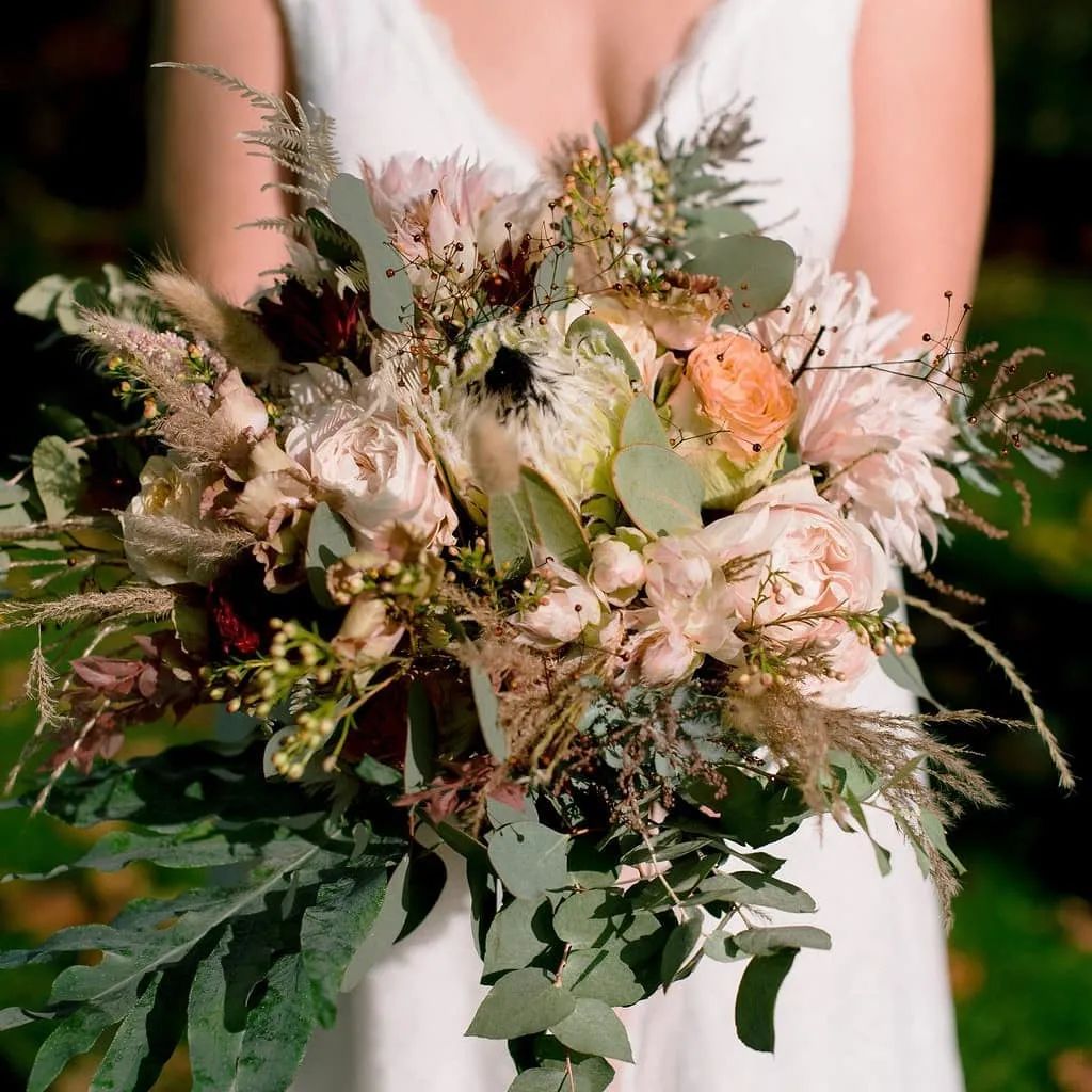 Bouquet de mariée de fleurs pâles et de feuillage sur une robe blanche