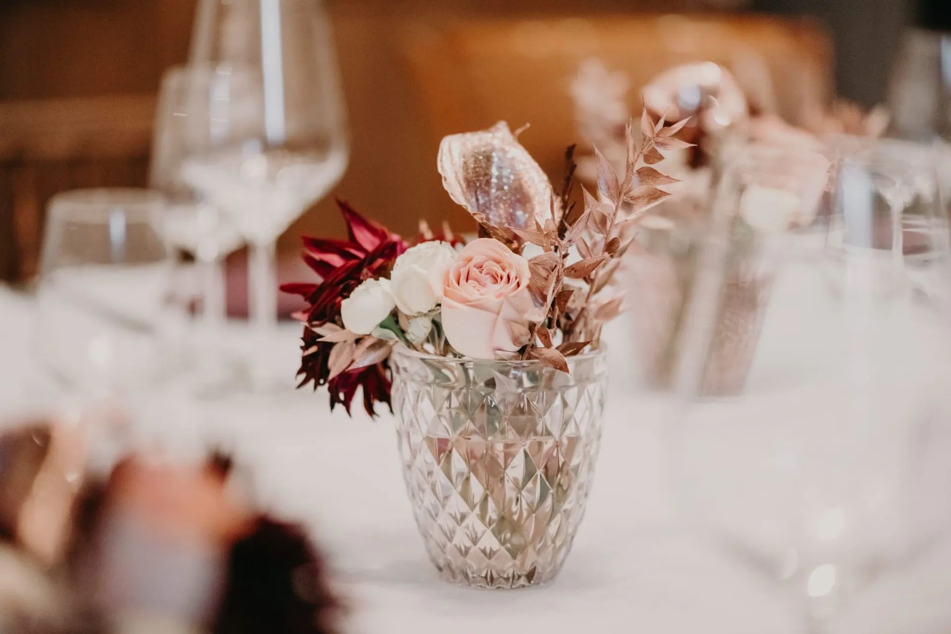 Petite composition de fleurs dans un verre taillé sur une table de réception