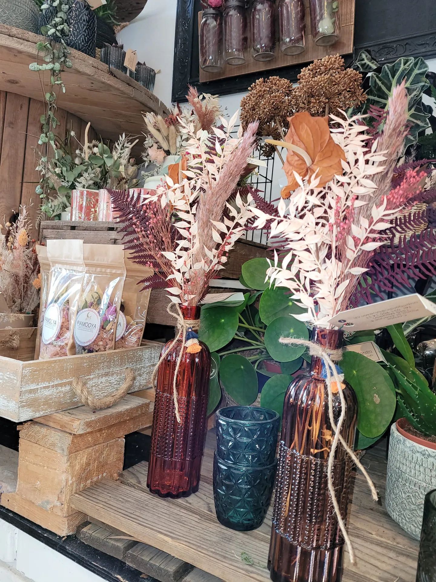 Fleurs séchées roses et blanches dans deux bouteilles en verre ambré