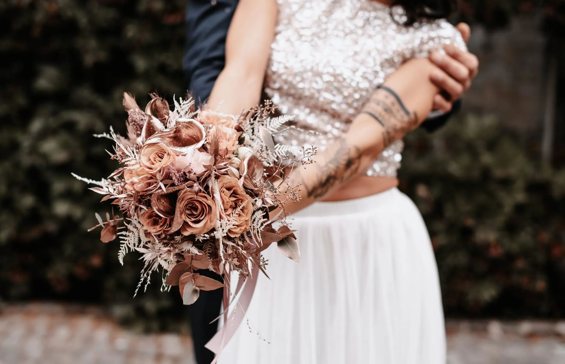 Bouquet de roses terracotta tenu par une mariée, ruban rose pâle
