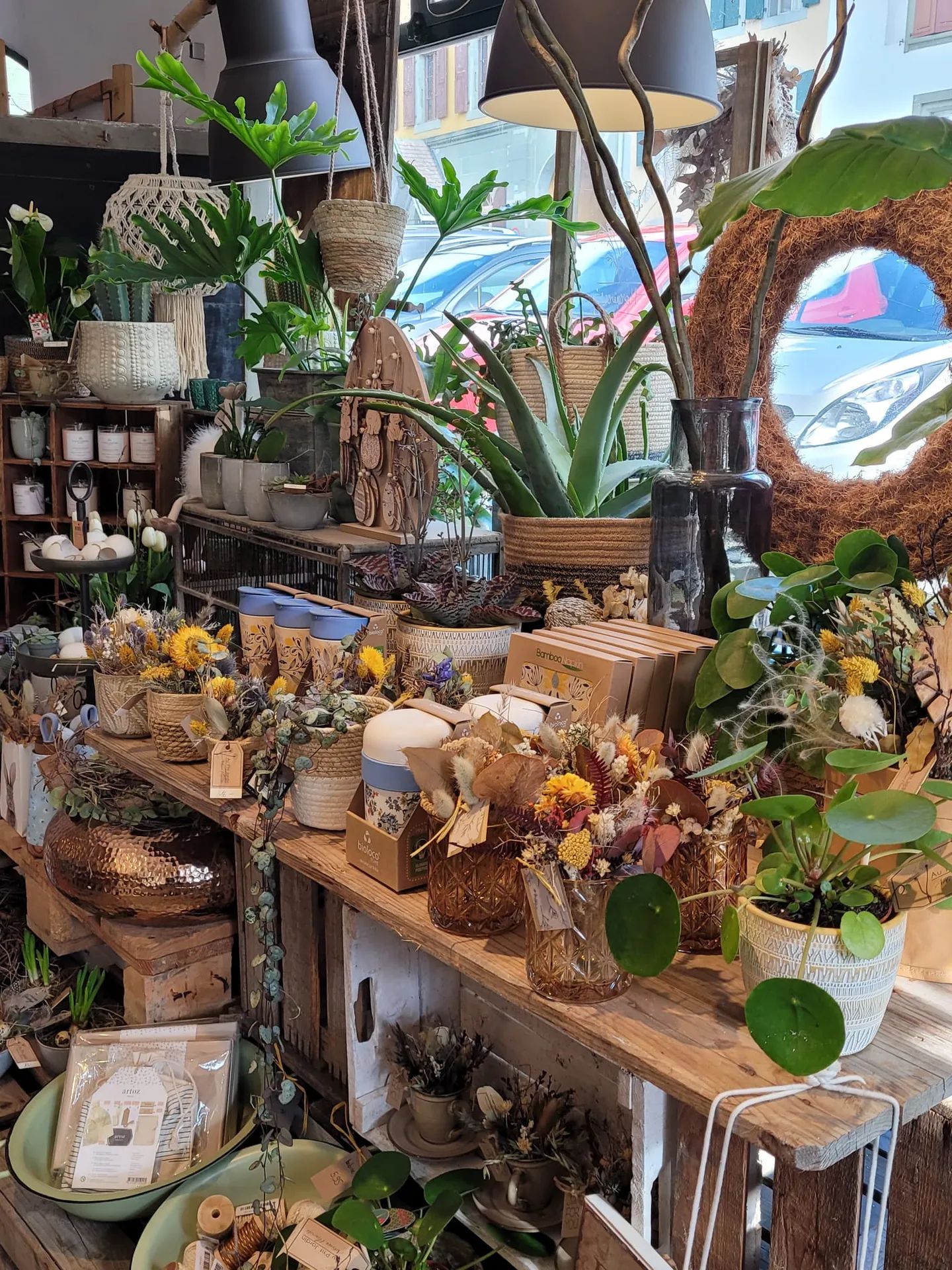 Longue table en bois de la boutique, plantes, bougies et objets de décoration