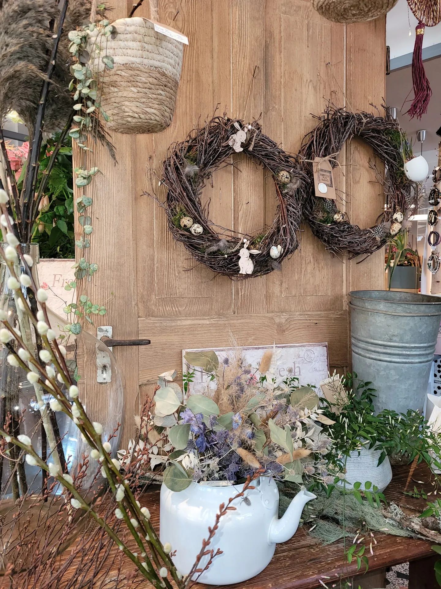 Couronnes de branches sur une porte en bois, bouquet dans une théière blanche