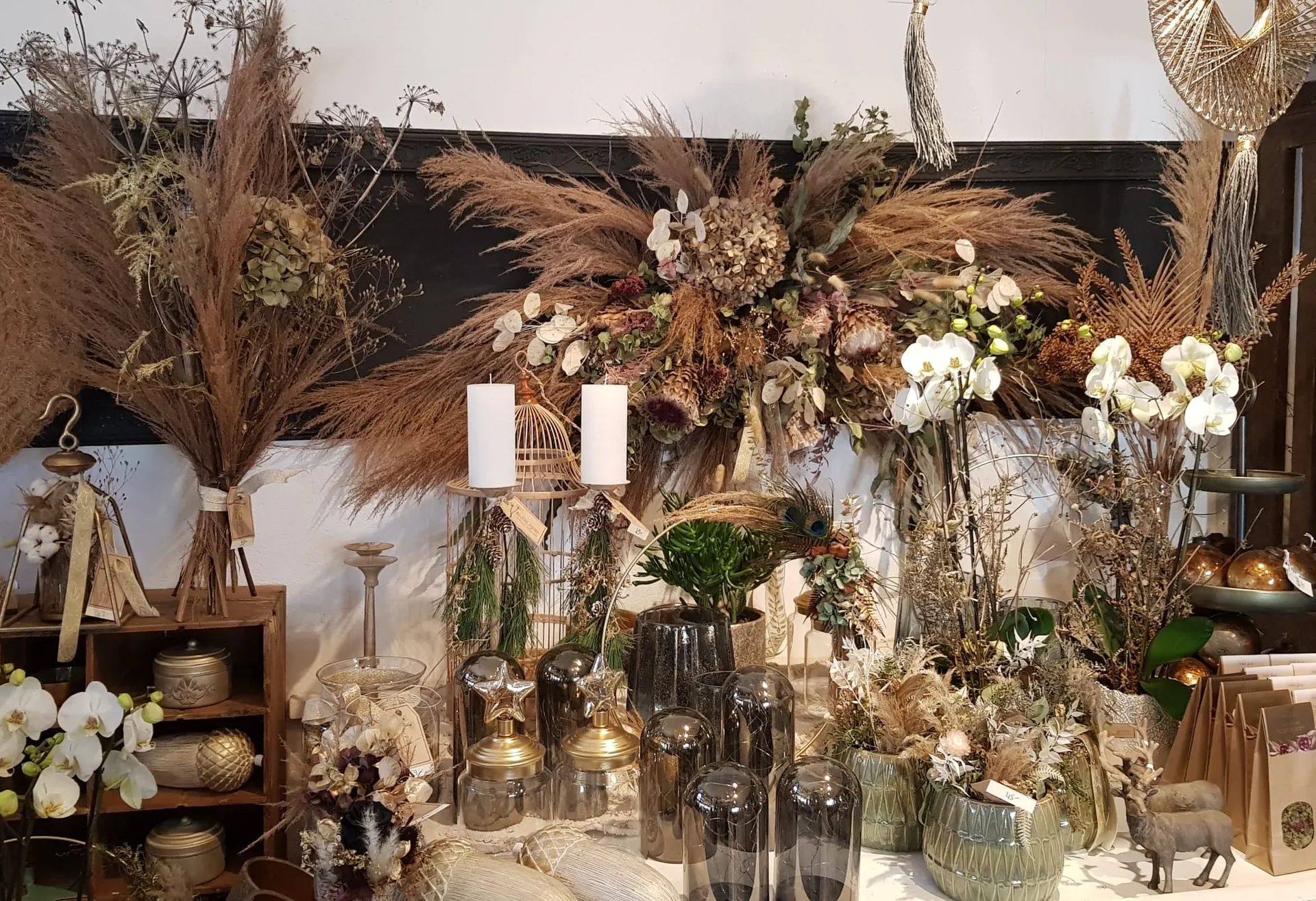 Table de la boutique avec pampas séchées, orchidées blanches et bougies