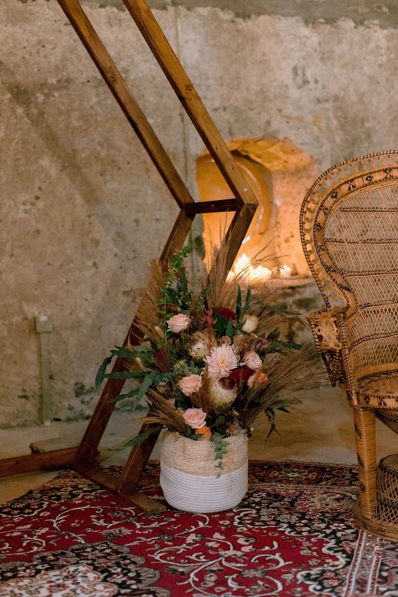Composition de fleurs au pied d’une arche en bois, sur un tapis rouge