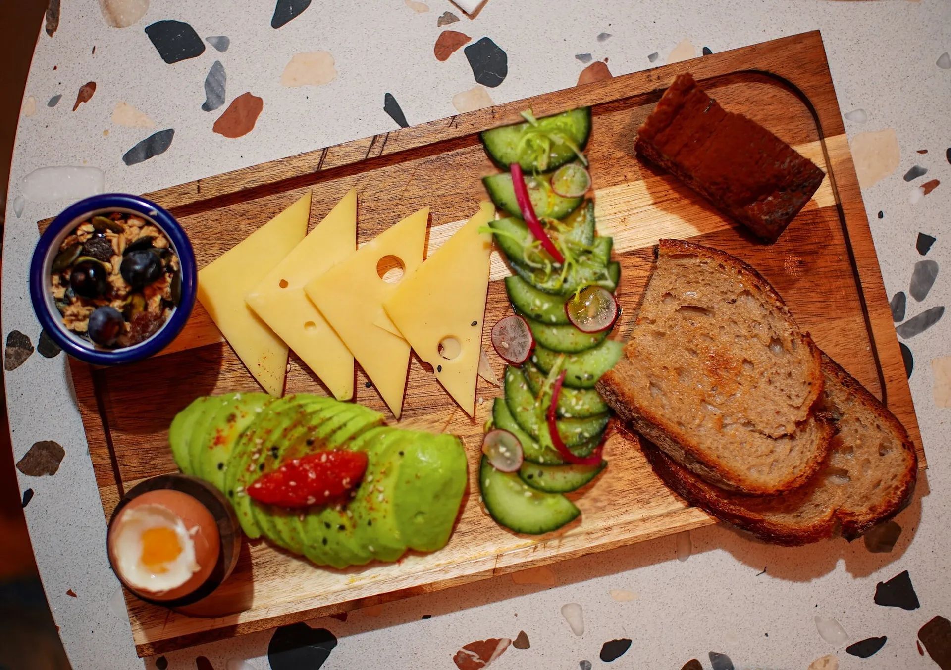 Planche vue du dessus : avocat, fromage, pain au levain et œuf