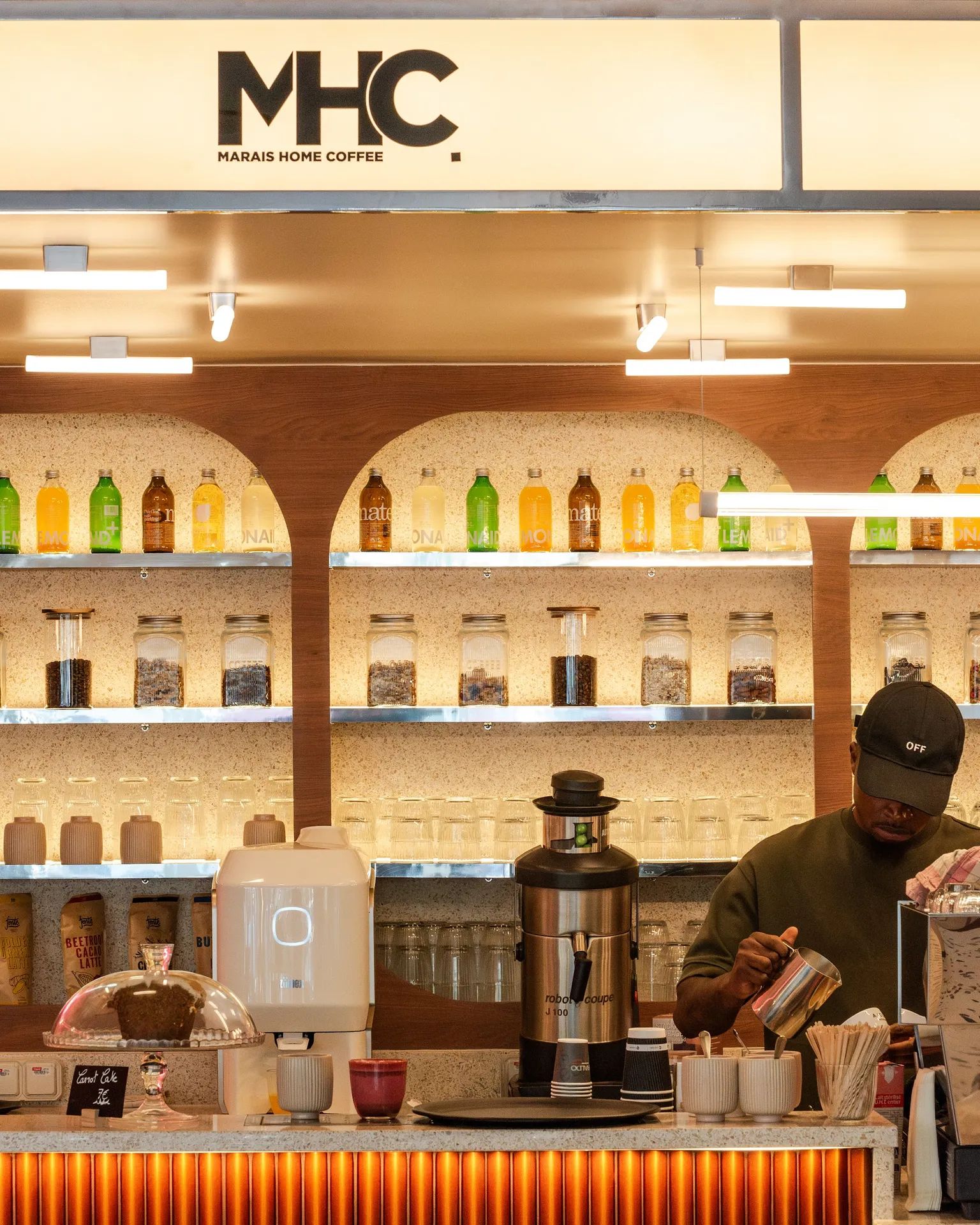 Le comptoir, ses arches rétroéclairées et le barista au travail